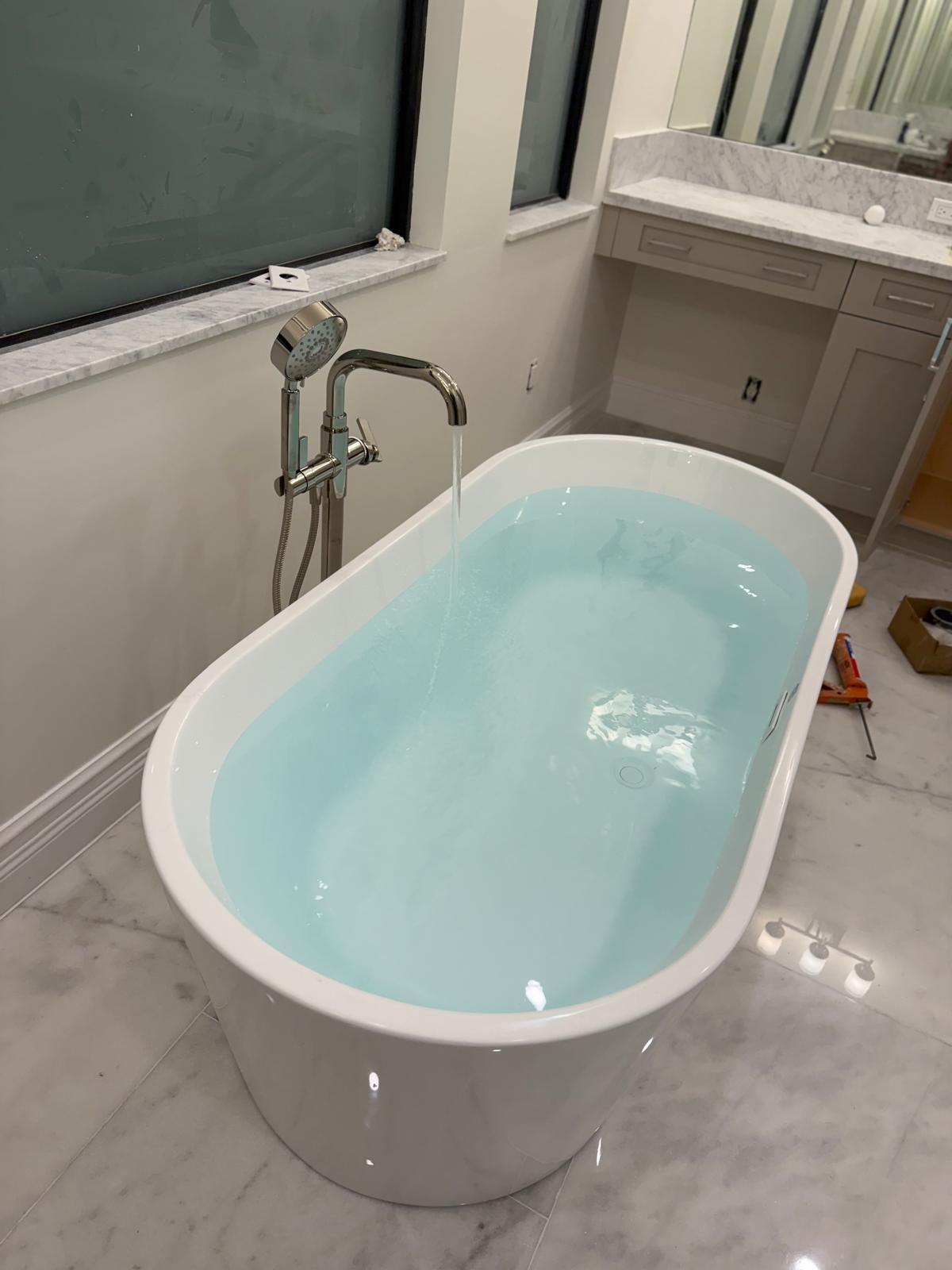 Freestanding soaking tub with a floor-mounted faucet
